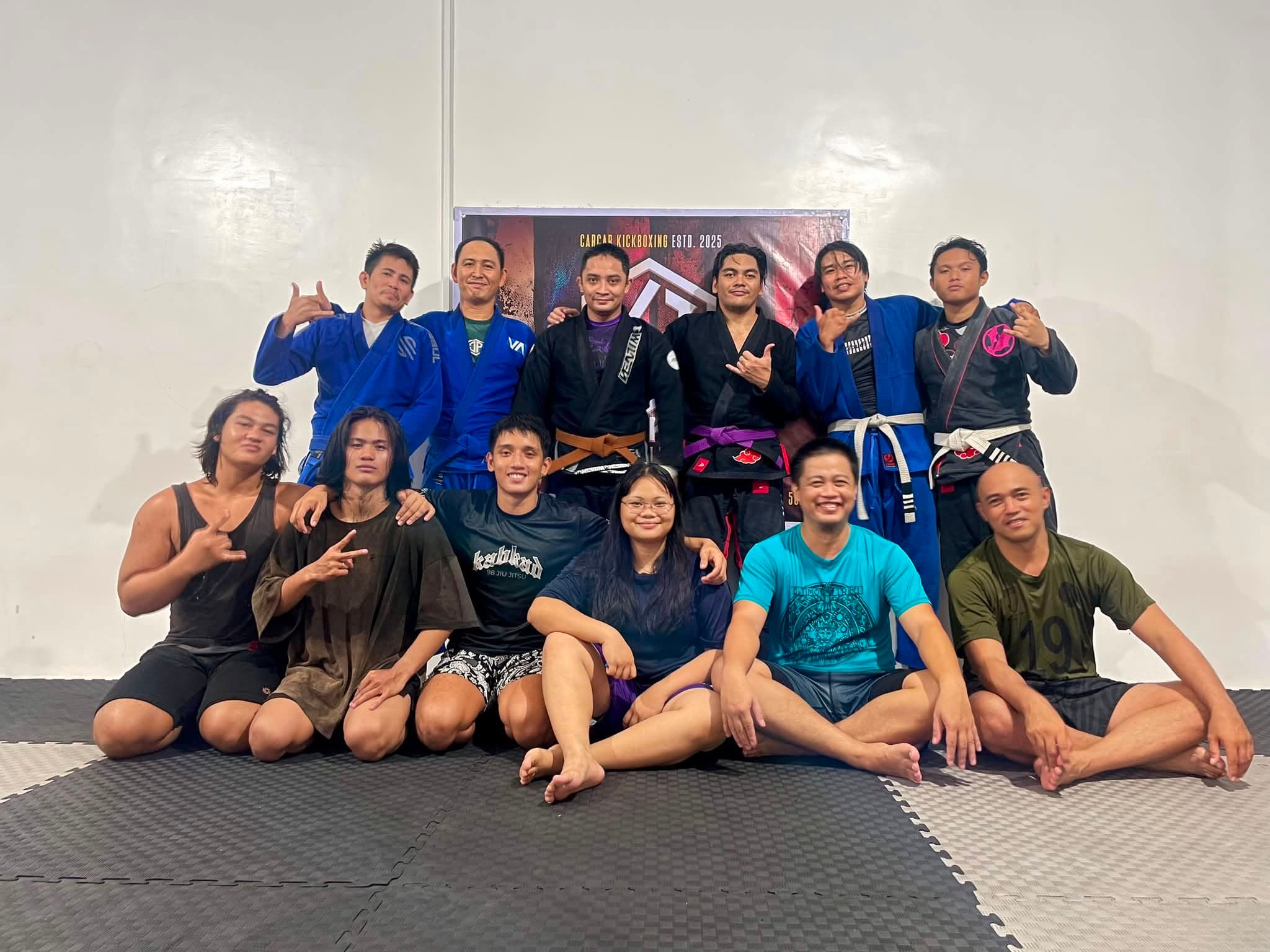 The Kabkad team posing on the mats, some in gis with white, blue, purple and brown belts